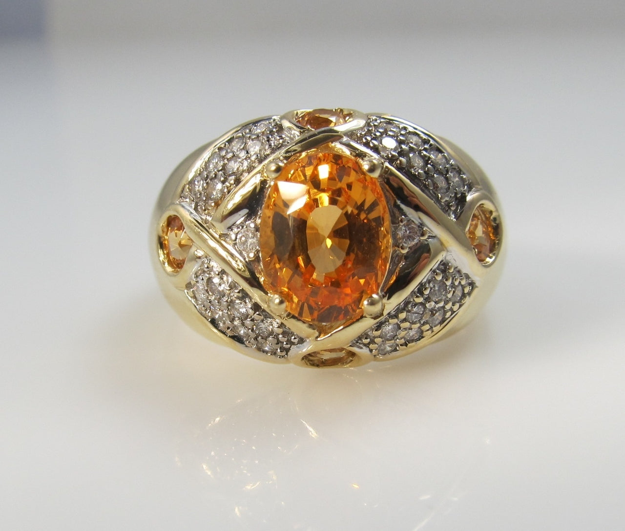 Modern estate 14k gold ring with a 2.50ct center orange sapphire and diamonds